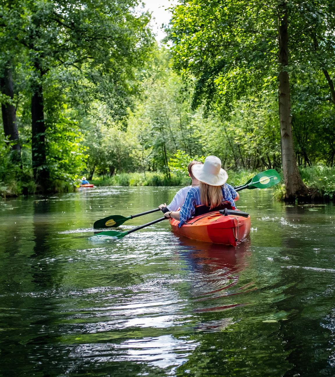 Paddler fahren mit ihren Booten über einen Seitenarm der Spree.