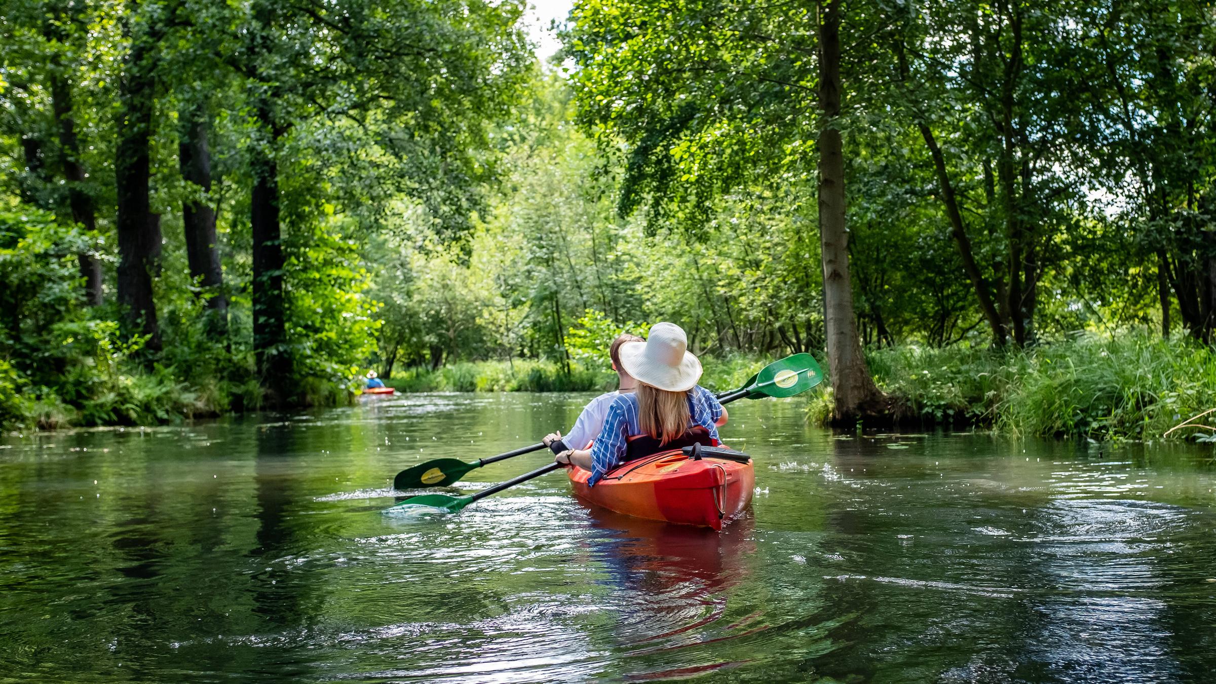 Paddler fahren mit ihren Booten über einen Seitenarm der Spree.