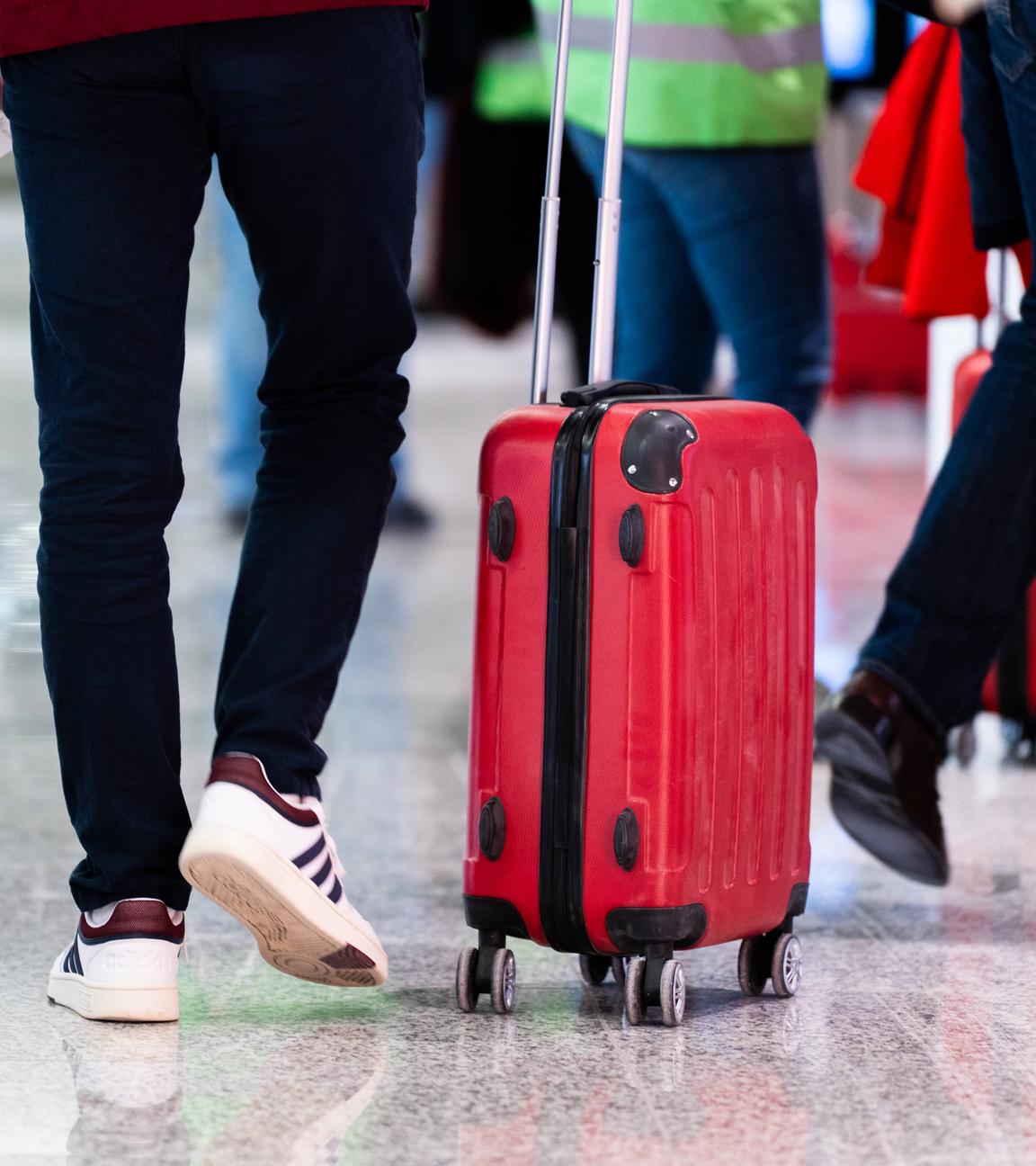 Reisende mit Rollkoffern am Flughafen