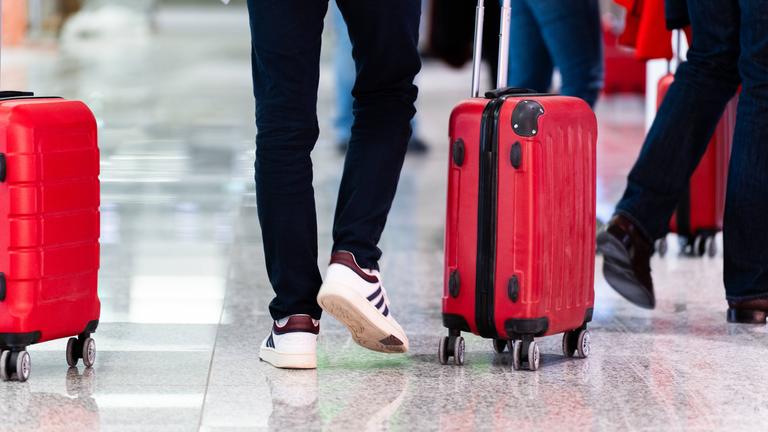Reisende mit Rollkoffern am Flughafen