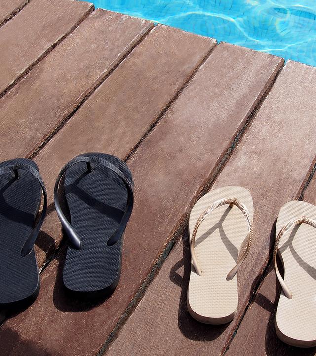 Zwei Paar Flipflops am Pool