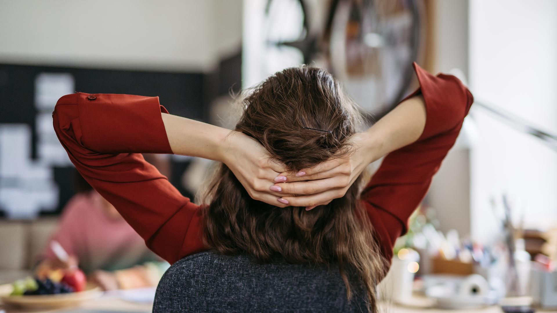 Junge Frau entspannt sich am Arbeitsplatz - Symbol Work-Life-Balance