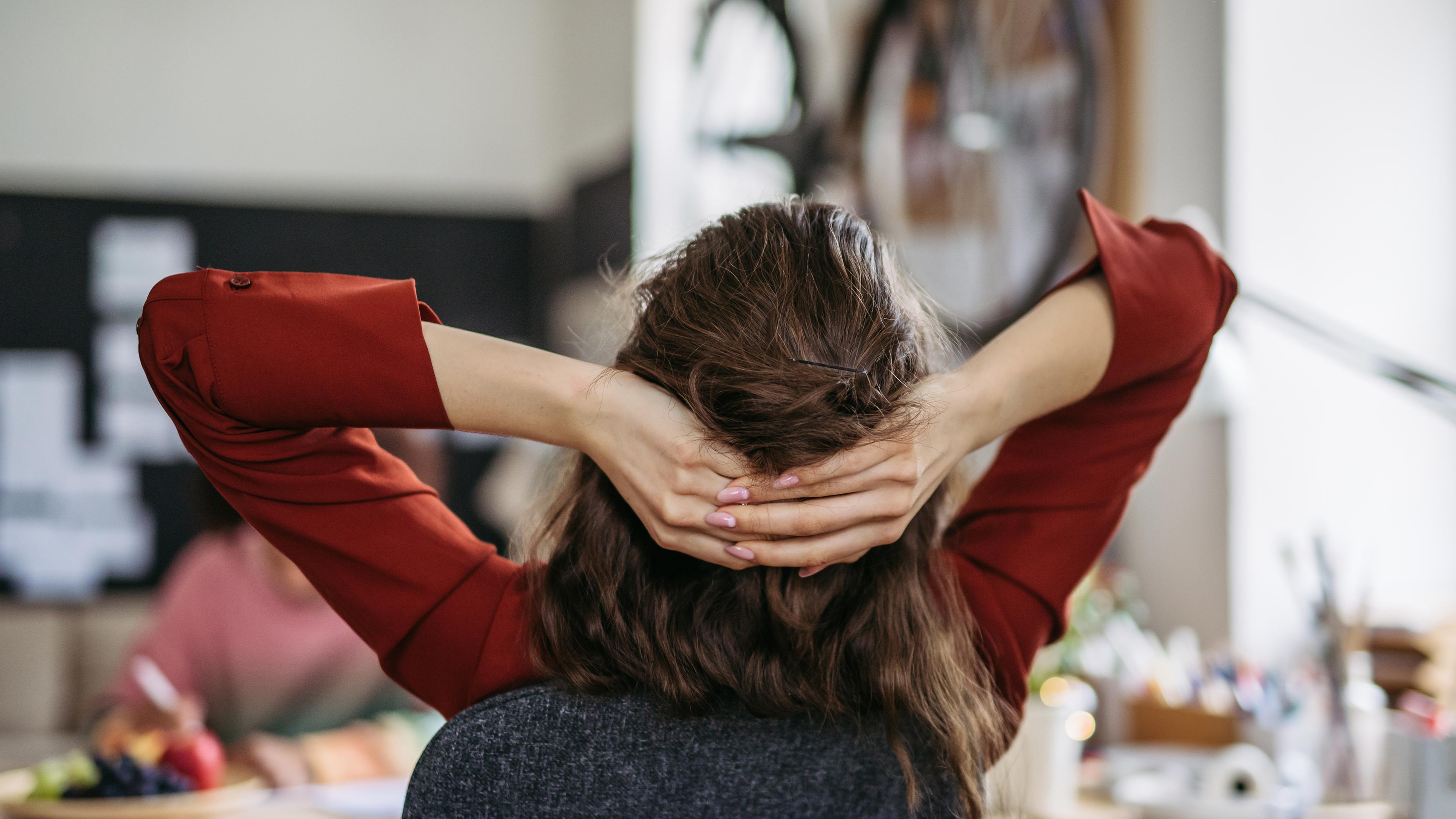 Junge Frau entspannt sich am Arbeitsplatz - Symbol Work-Life-Balance