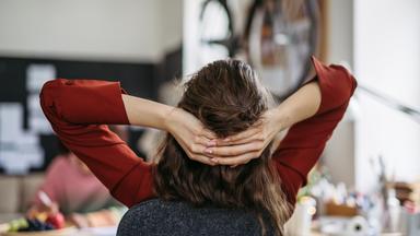 Junge Frau entspannt sich am Arbeitsplatz - Symbol Work-Life-Balance