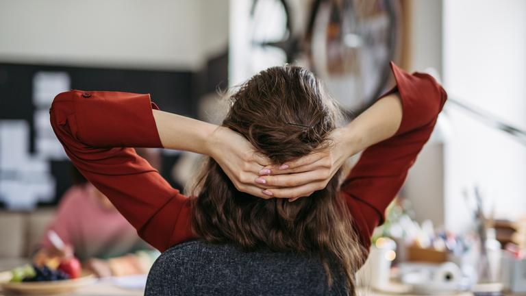 Junge Frau entspannt sich am Arbeitsplatz - Symbol Work-Life-Balance
