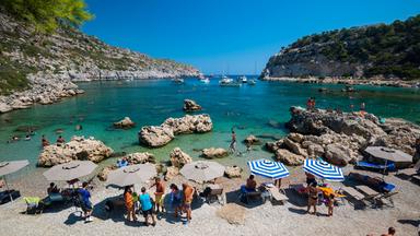 Touristen unter Sonnenschirmen am Strand von Rhodos