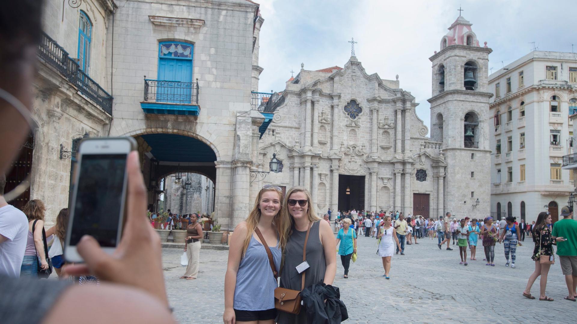 Zwei Frauen lassen sich vor der Kathedrale in Havanna fotografieren.
