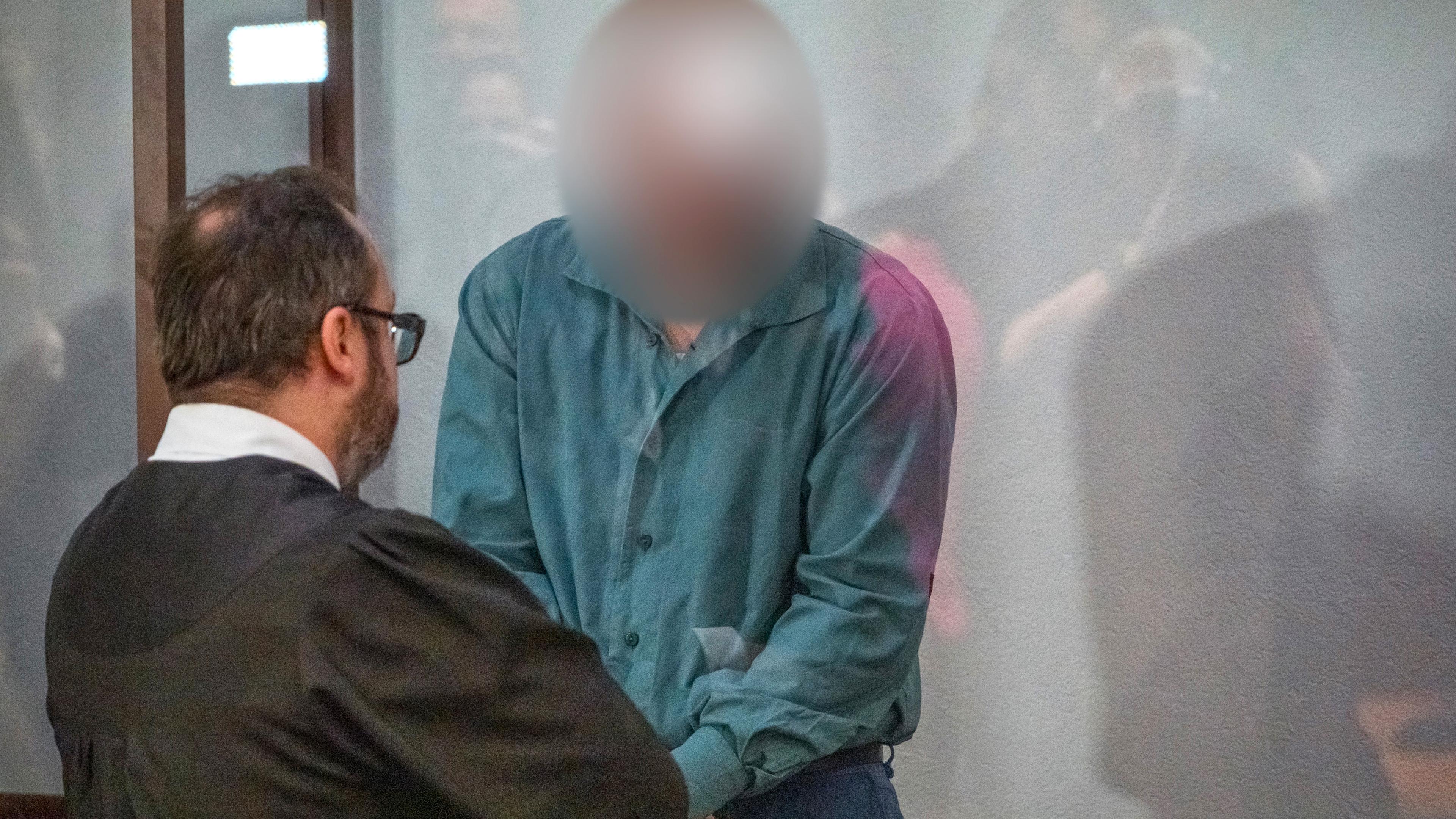 Der Rechtsanwalt des Angeklagten bespricht sich mit seinem Mandanten (r)