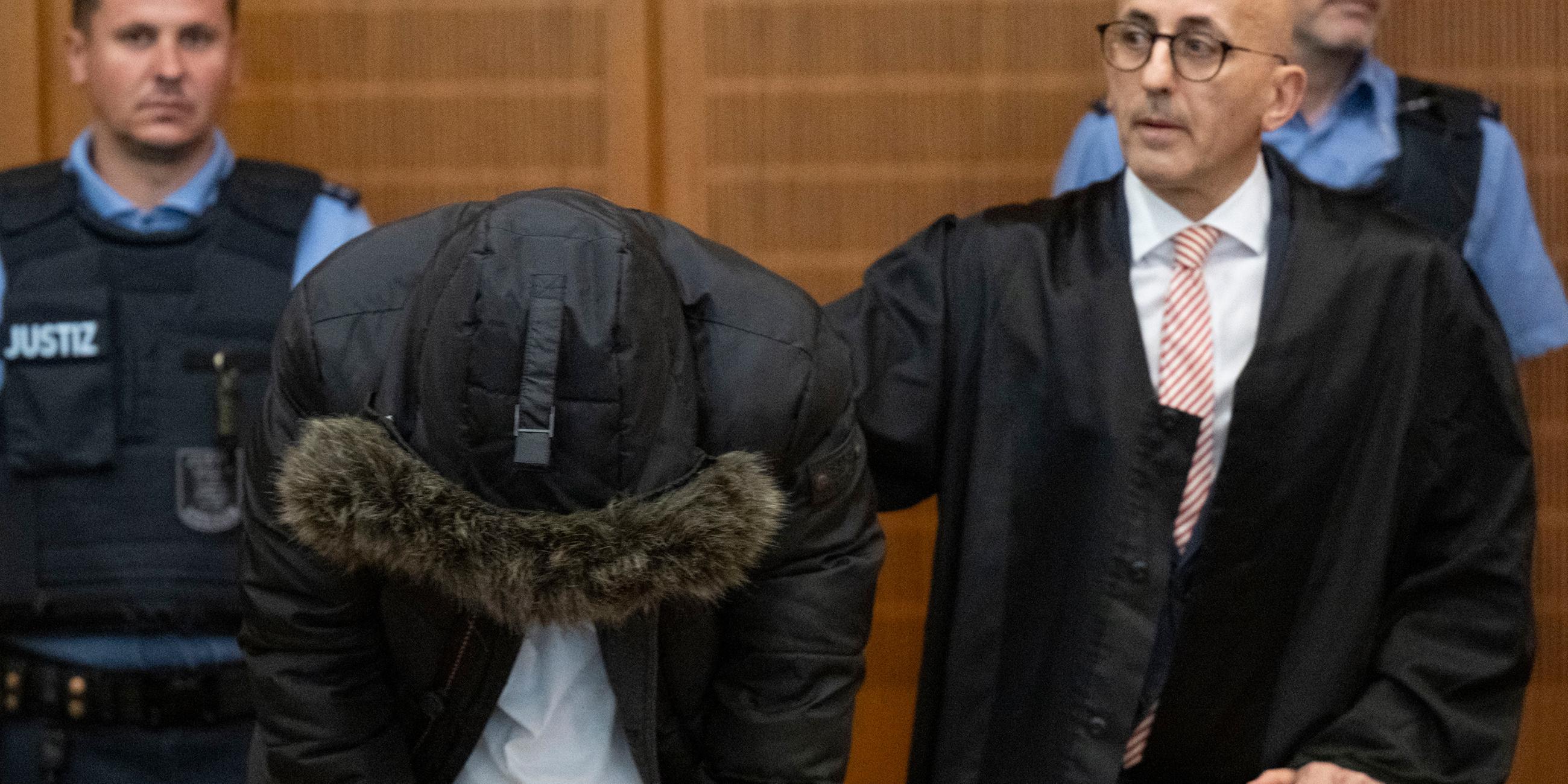 16.06.2025, Hessen, Frankfurt/Main: Der angeklagte, syrische Arzt (2.v.l.) steht vor der Urteilsverkündung neben seinem Anwalt Oussama Al-Agi (2.v.r.) im Oberlandesgericht.