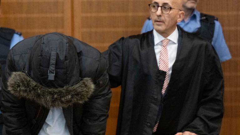 16.06.2025, Hessen, Frankfurt/Main: Der angeklagte, syrische Arzt (2.v.l.) steht vor der Urteilsverkündung neben seinem Anwalt Oussama Al-Agi (2.v.r.) im Oberlandesgericht.