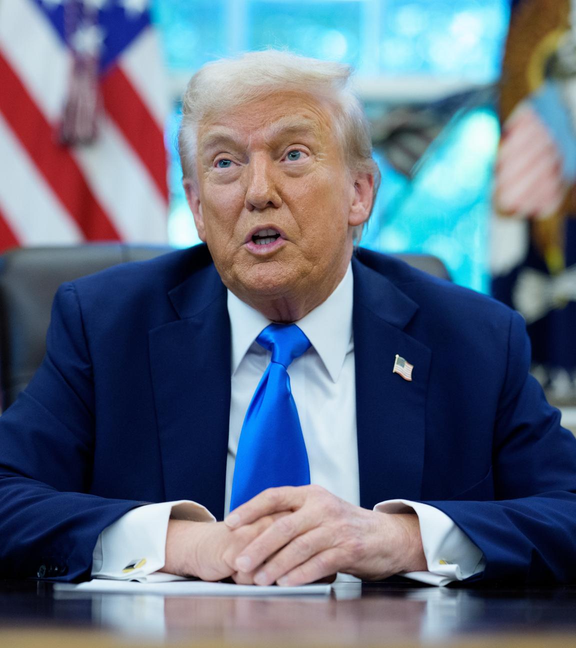 Eine Aufnahme von Trump, wie er an seinem Tisch sitzt und spricht,