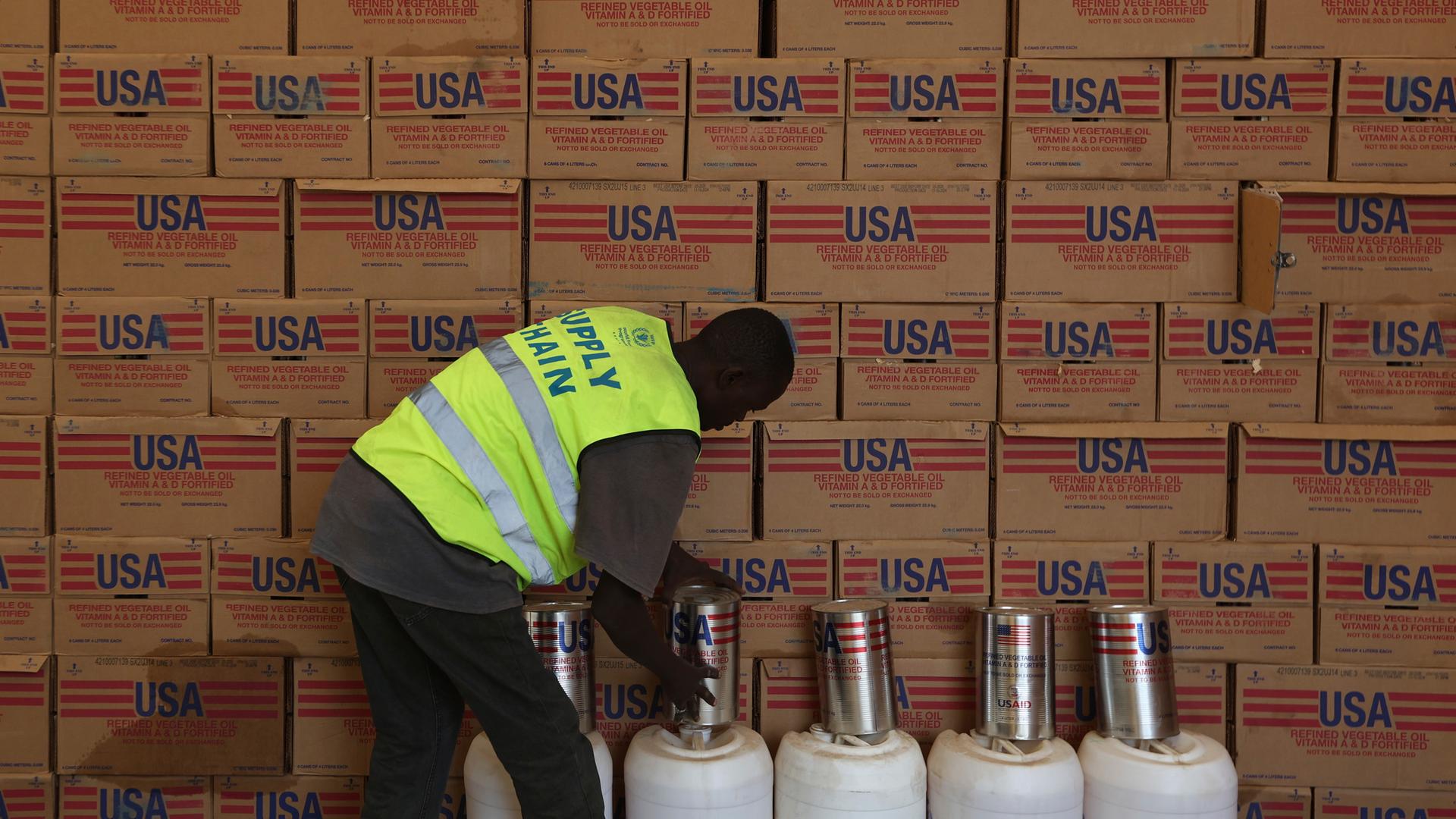 Ein Mann sortiert in einer Lagerhalle Hilfsgüter von der US-Entwicklungshilfe USAID.