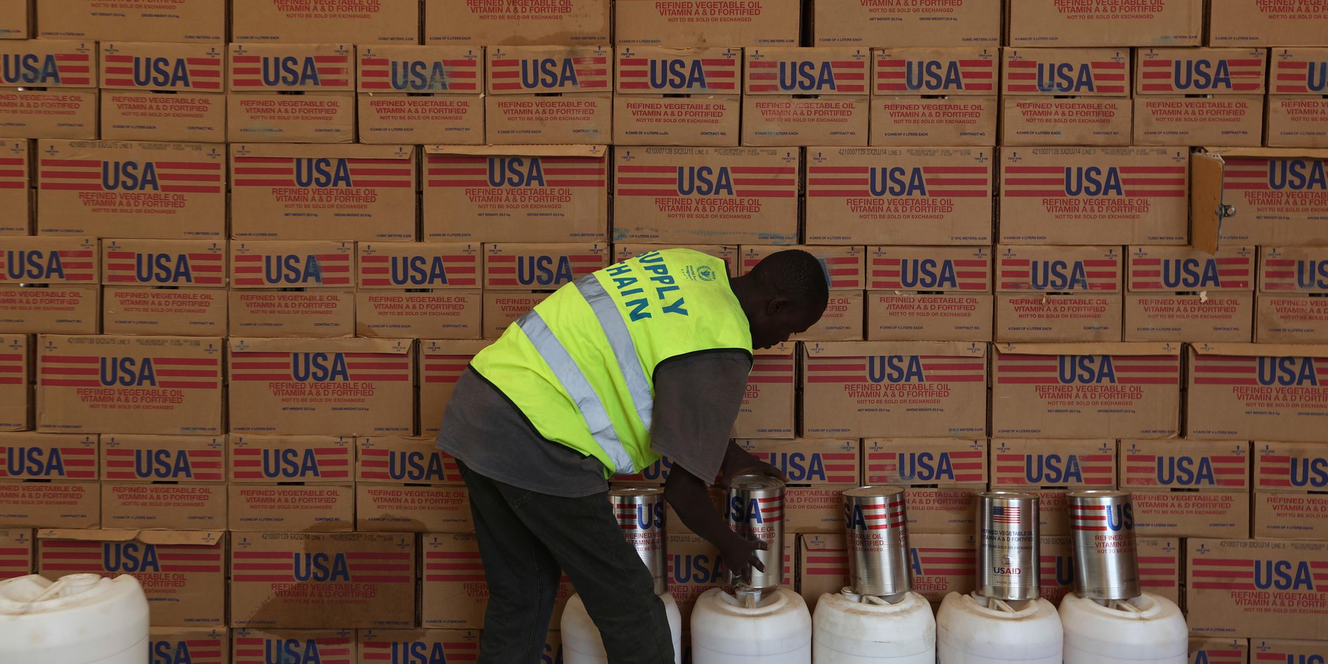 Ein Mann sortiert in einer Lagerhalle Hilfsgüter von der US-Entwicklungshilfe USAID.