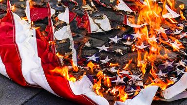 Eine amerikanische Flagge wird während eines Marsches für Jayland Walker am 6. Juli 2022 in New York verbrannt
