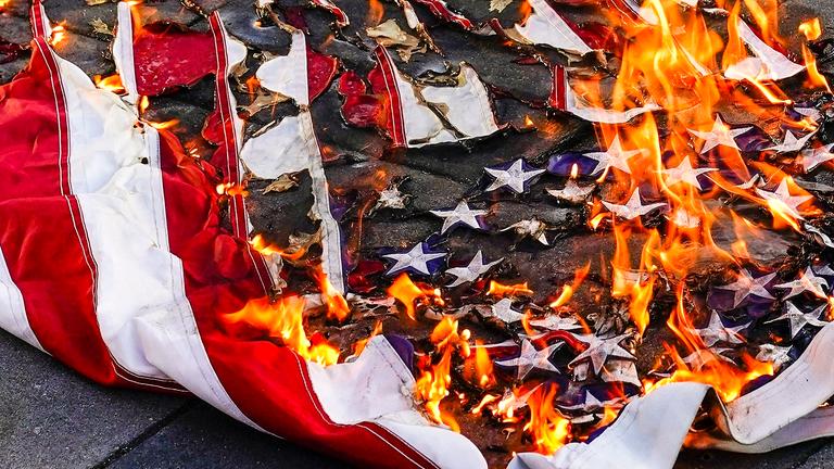 Eine amerikanische Flagge wird während eines Marsches für Jayland Walker am 6. Juli 2022 in New York verbrannt