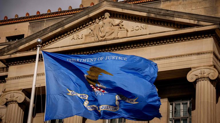 Das US-Justizministeriumsgebäude mit einer Flagge des Ministeriums, die vor dem gebäude steht.
