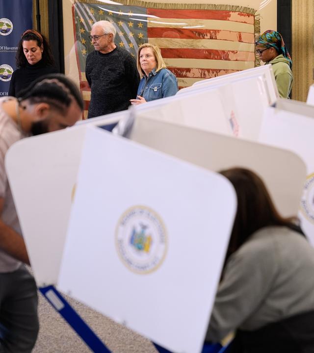 Menschen in den USA stehen hinter Wahlkabinen Schlange.