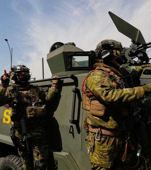 Irakische Polizeibeamte fahren in einem mit Nationalflaggen und Bändern geschmückten Sicherheitsfahrzeug im Rahmen eines Konvois durch die irakische Hauptstadt, um den vollständigen Abzug der US-Truppen aus dem Irak zu feiern.