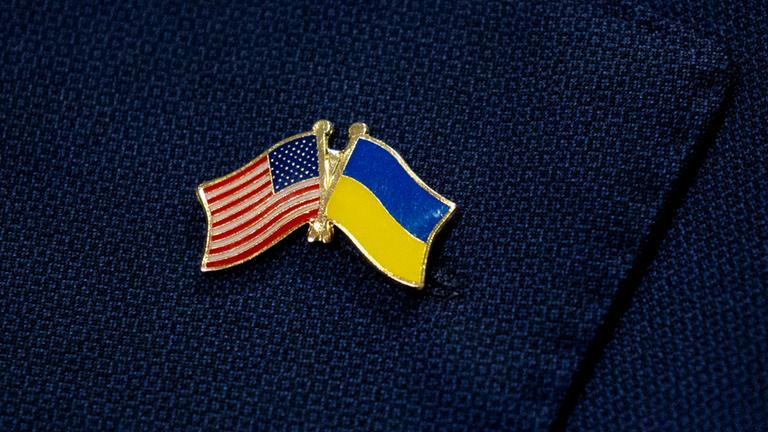 Ein Pin mit der US-amerikanischen und der ukrainischen Nationalflagge ist zu sehen.