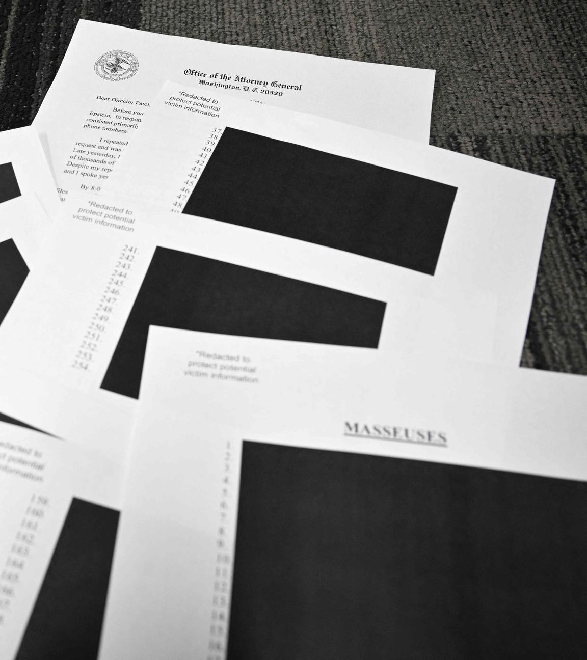 Redigierte Dokumente des Jeffrey Epstein-Falls liegen auf einem Tisch in schwarz-weiß.
