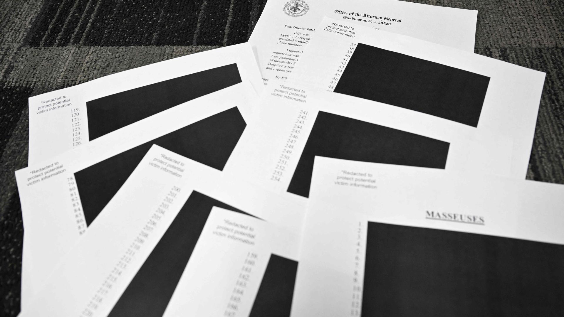 Redigierte Dokumente des Jeffrey Epstein-Falls liegen auf einem Tisch in schwarz-weiß.