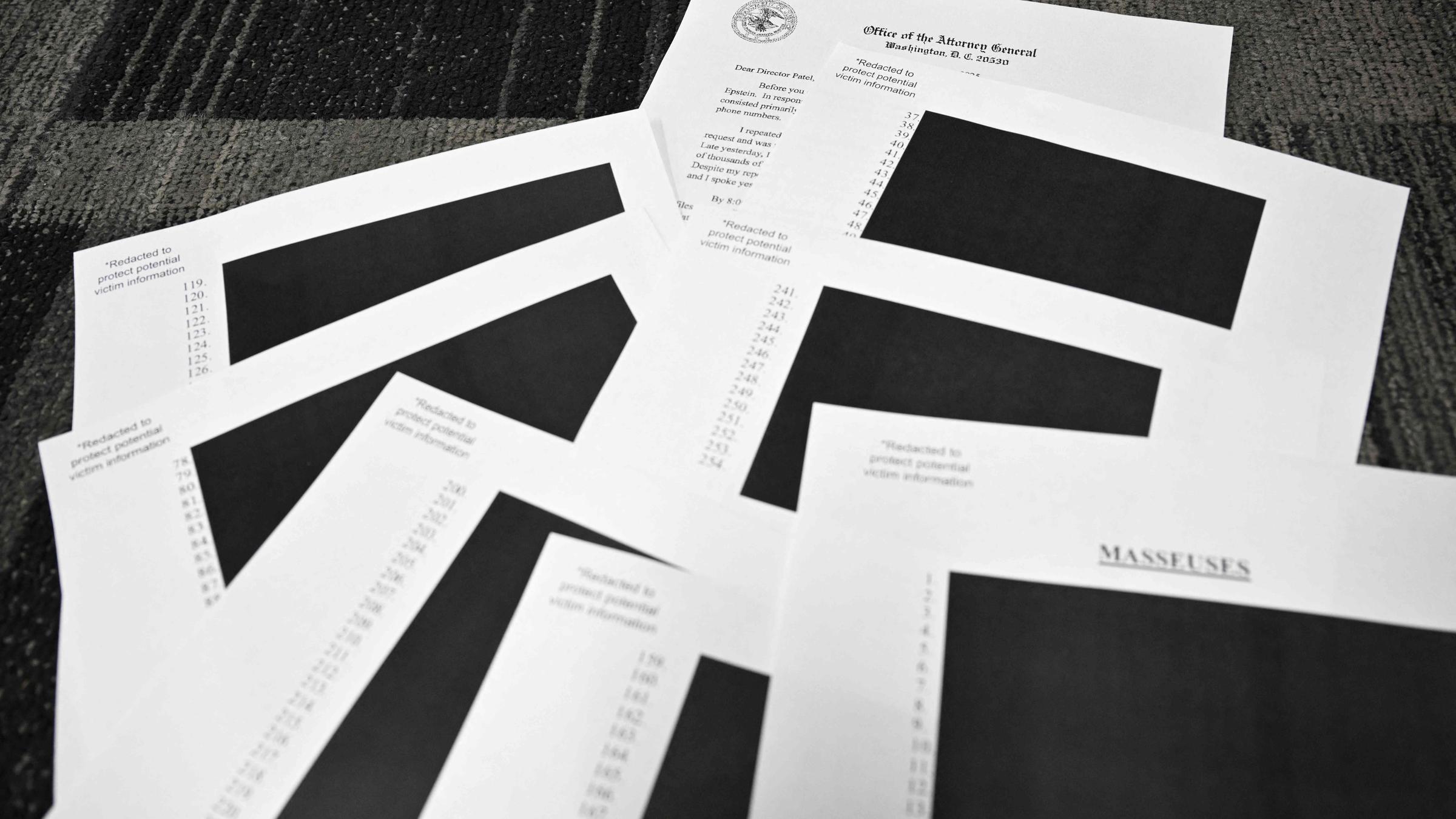 Redigierte Dokumente des Jeffrey Epstein-Falls liegen auf einem Tisch in schwarz-weiß.