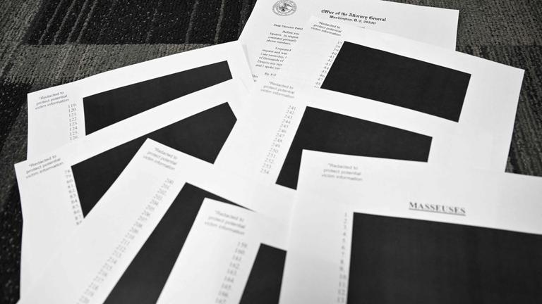 Redigierte Dokumente des Jeffrey Epstein-Falls liegen auf einem Tisch in schwarz-weiß.