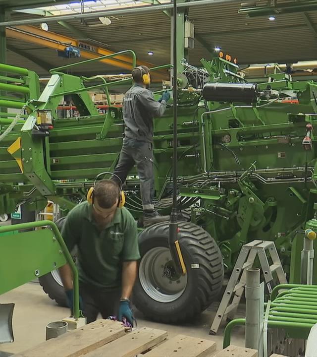 Arbeiter bauen an großer Maschine aus Stahl
