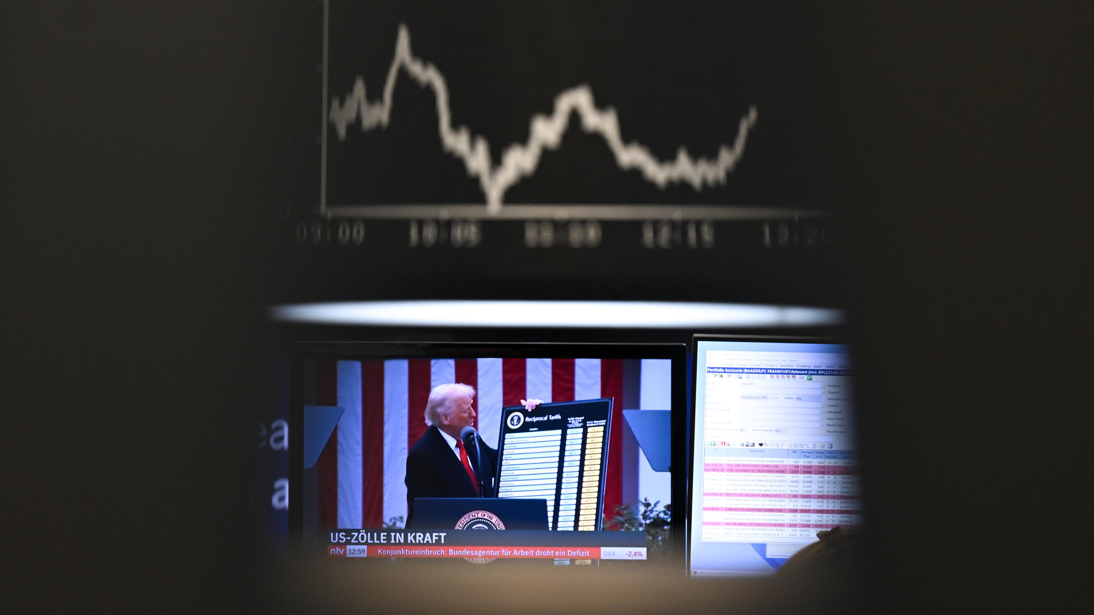 09.04.2025, Hessen, Frankfurt/Main: US-Präsident Trump ist auf einem Bildschirm auf dem Parkett der Frankfurter Wertpapierbörse vor der Anzeigetafel mit der Dax-Kurve zu sehen.