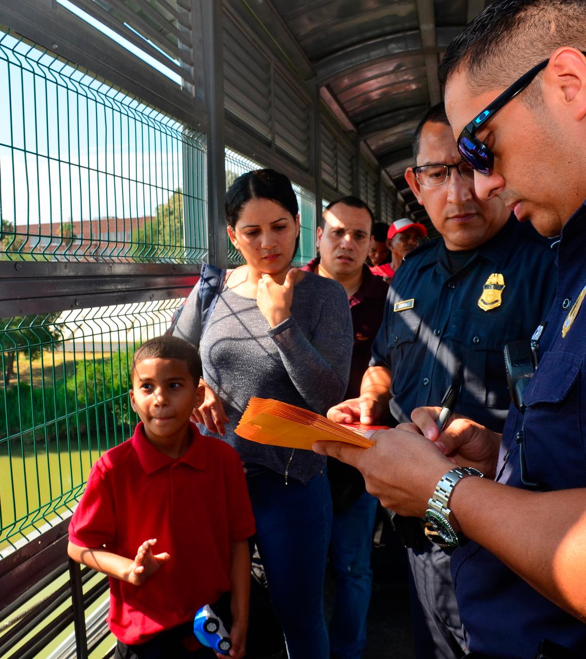 Zoll- und Grenzschutzbeamte der USA untersuchen auf einer Brücke zwischen Mexiko und den USA die Papiere einer kubanischen Familie, die zuvor Asyl beantragt hat. 