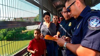 Zoll- und Grenzschutzbeamte der USA untersuchen auf einer Brücke zwischen Mexiko und den USA die Papiere einer kubanischen Familie, die zuvor Asyl beantragt hat. 