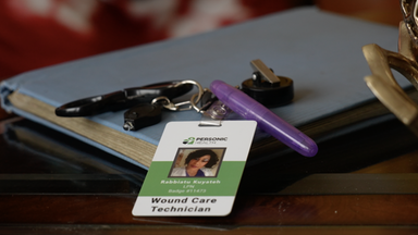 Das Bild zeigt Rabbiatu Kuyatehs Arbeitsausweis, der auf einem Tisch liegt. Auf dem Ausweis steht ihr Name und die Jobbeschreibung "Wound Care Technician".