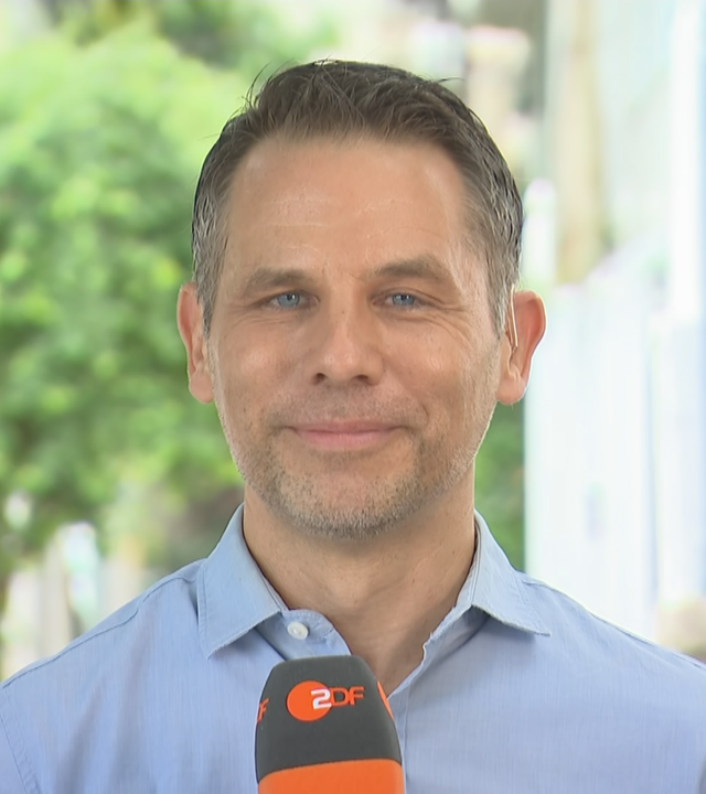 ZDF-Korrespondent Christoph Röckerath mit Mikrofon aus Brasilien, in Rio de Janeiro draußen.