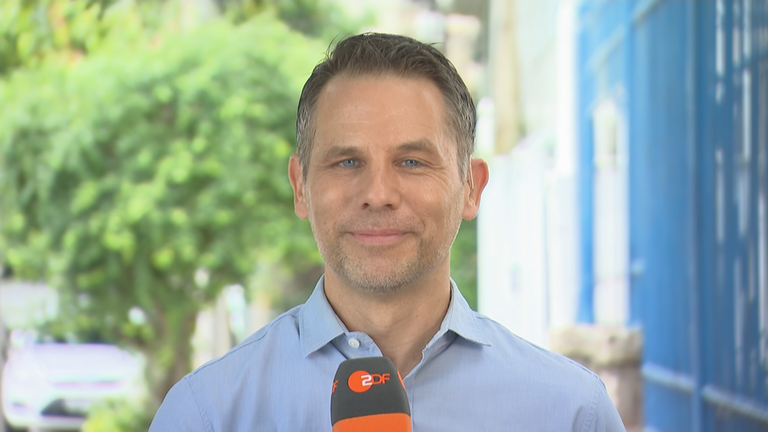 ZDF-Korrespondent Christoph Röckerath mit Mikrofon aus Brasilien, in Rio de Janeiro draußen.