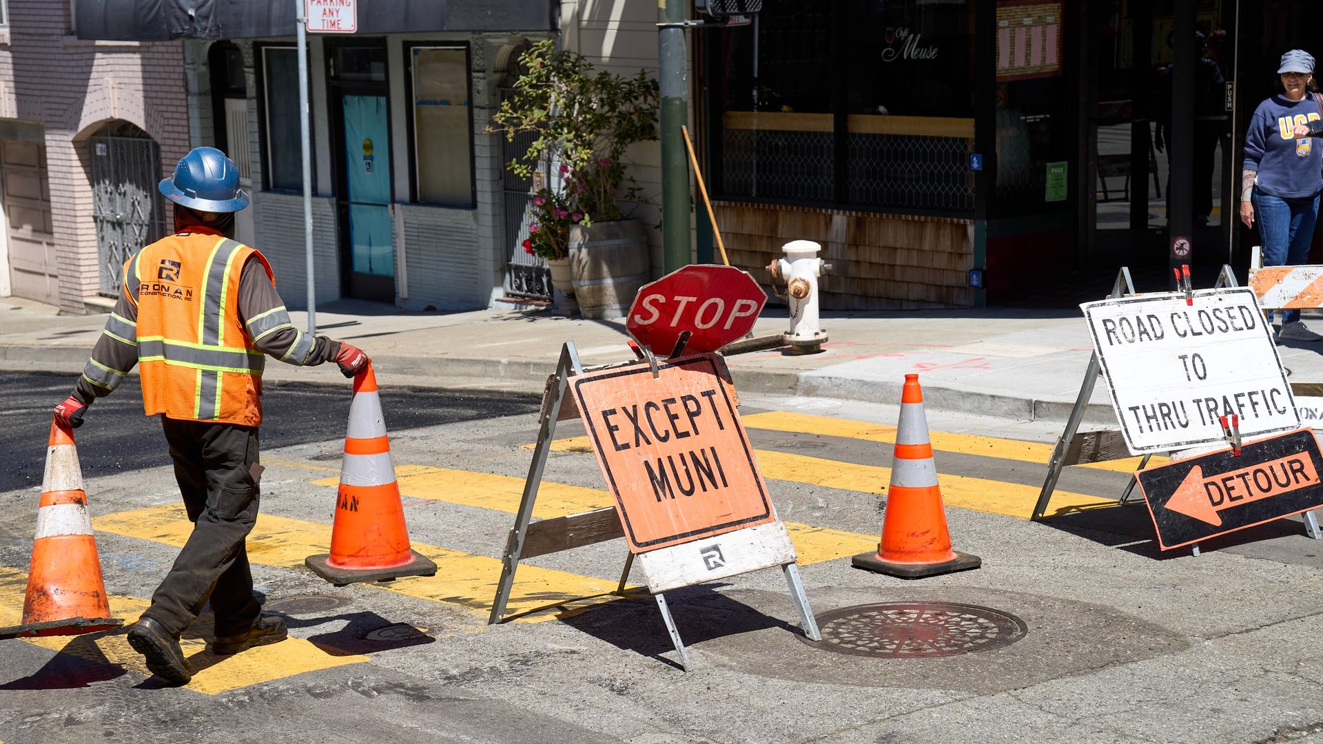 14. Juni 2024: Ein Bauarbeiter in Sicherheitskleidung platziert Warnkegel auf einer gesperrten Straße, um den Verkehr umzuleiten in San Francisco, USA.