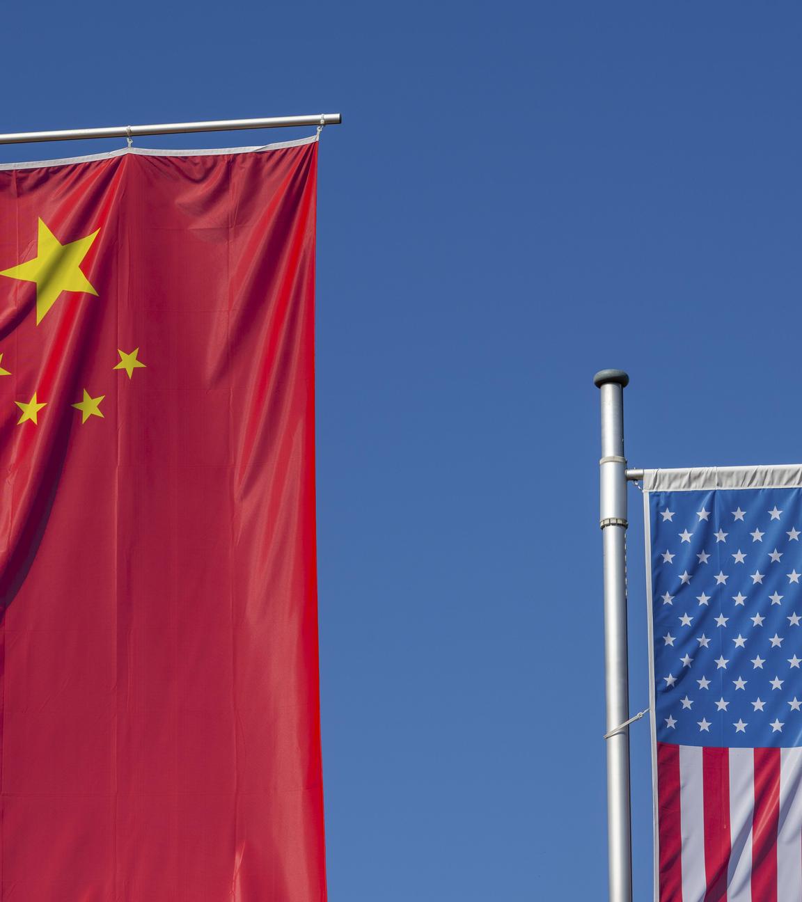Chinesische und Amerikanische Flagge wehen vor einem klaren, blauen Himmel