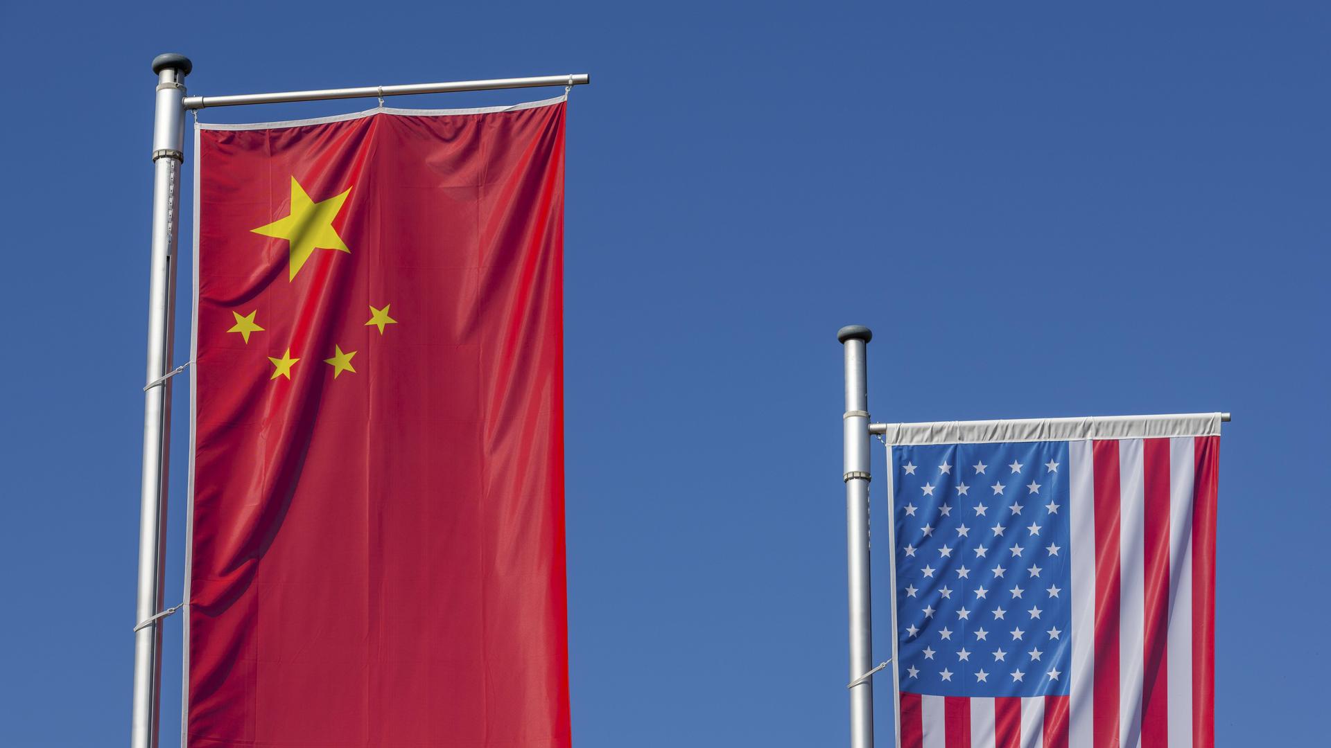 Chinesische und Amerikanische Flagge wehen vor einem klaren, blauen Himmel