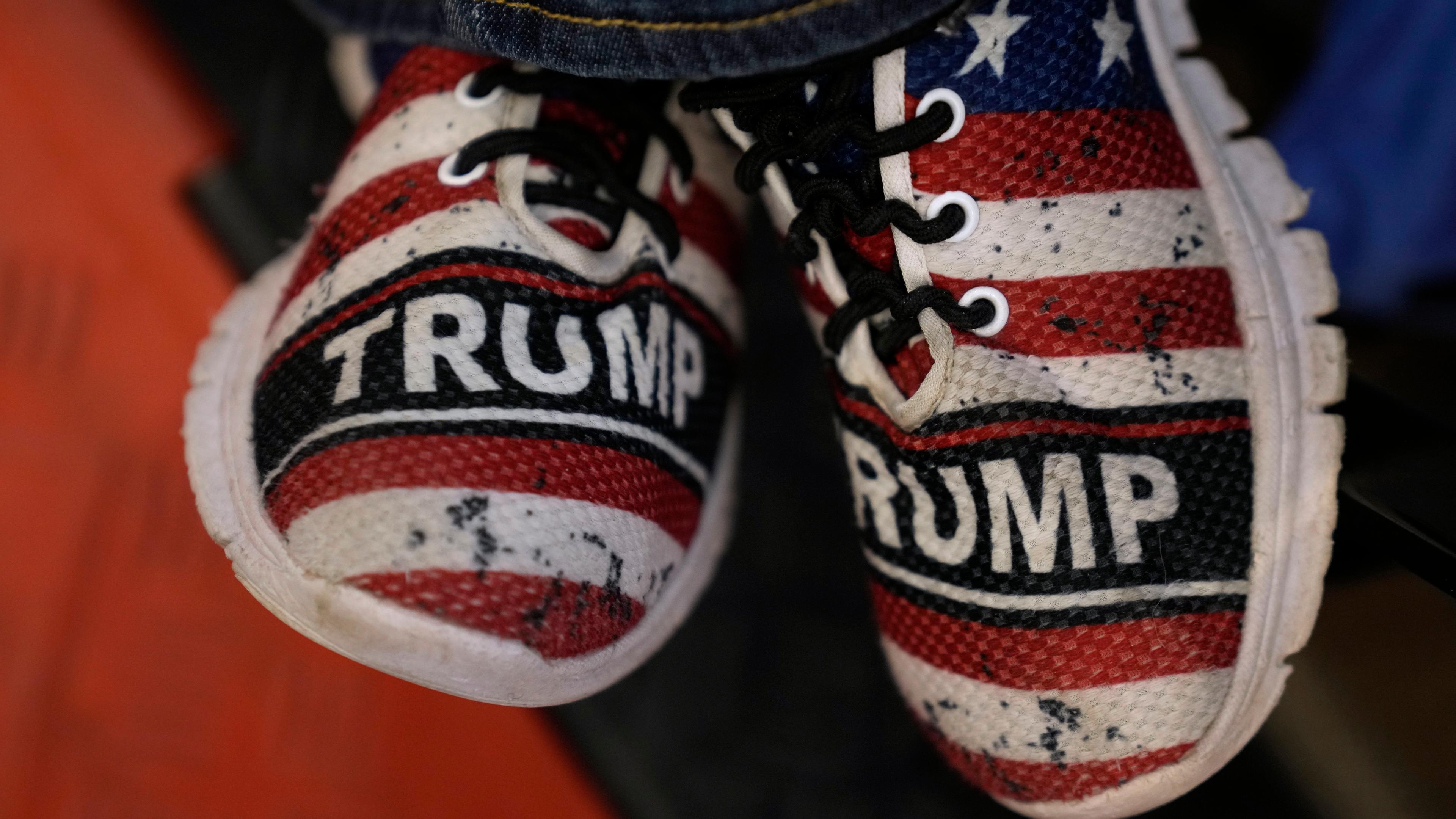 USA, Coralville: Kinderschuhe in den US-amerikanischen Nationalfarben und dem Schritzug mit dem Namen des ehemaligen US-Präsidenten Trump werden getragen vor einer Commit-to-Caucus-Kundgebung zu sehen in Coralville, Iowa.