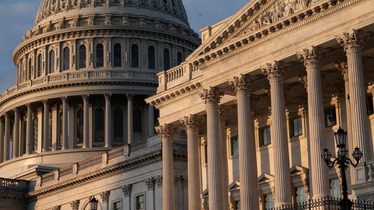 Blick auf das Friedensdenkmal und die Kuppel des US-Kapitols bei bewölktem Himmel.