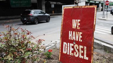 Das Bild zeigt ein rostiges Schild an einer Straßenkreuzung mit der Aufschrift "We have Diesel".