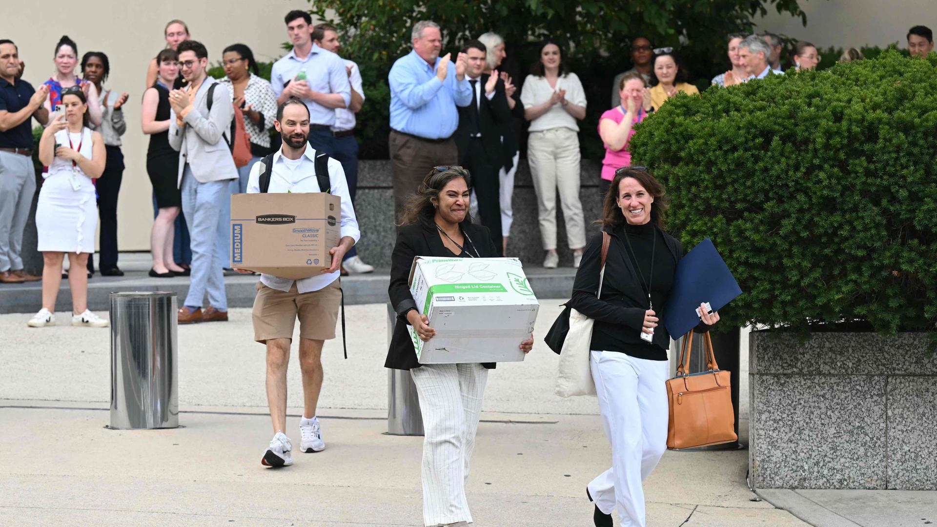 Von der US-Regierung entlassene Angestellte tragen ihre Sachen aus einem Gebäude in Washington DC.