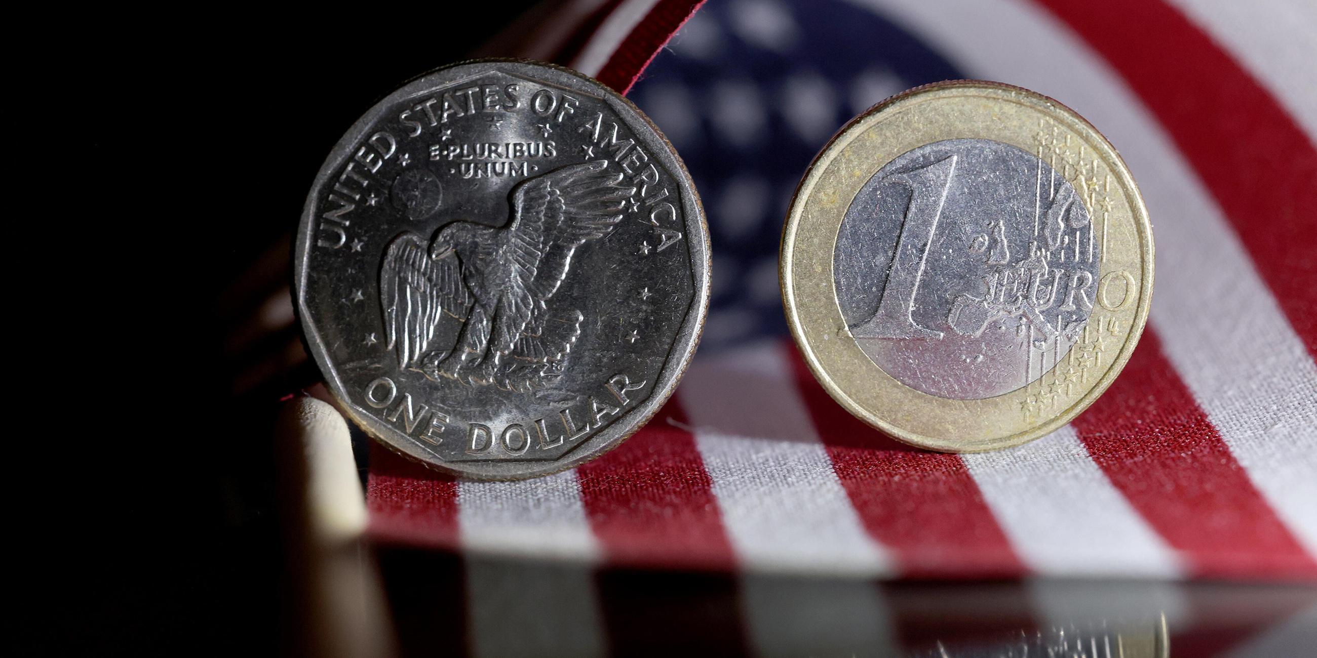 Eine 1 Dollar Münze (Münze) und eine 1 Euro Münze (Münze) stehen auf einer US Flagge.