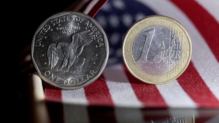 Eine 1 Dollar Münze (Münze) und eine 1 Euro Münze (Münze) stehen auf einer US Flagge.