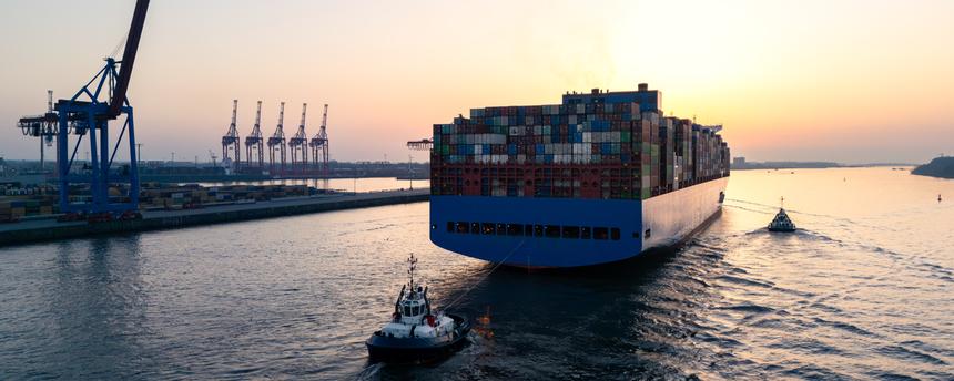 Luftaufnahme einer Drohne, die ein großes Containerschiff zeigt, das Hamburg auf der Elbe verlässt