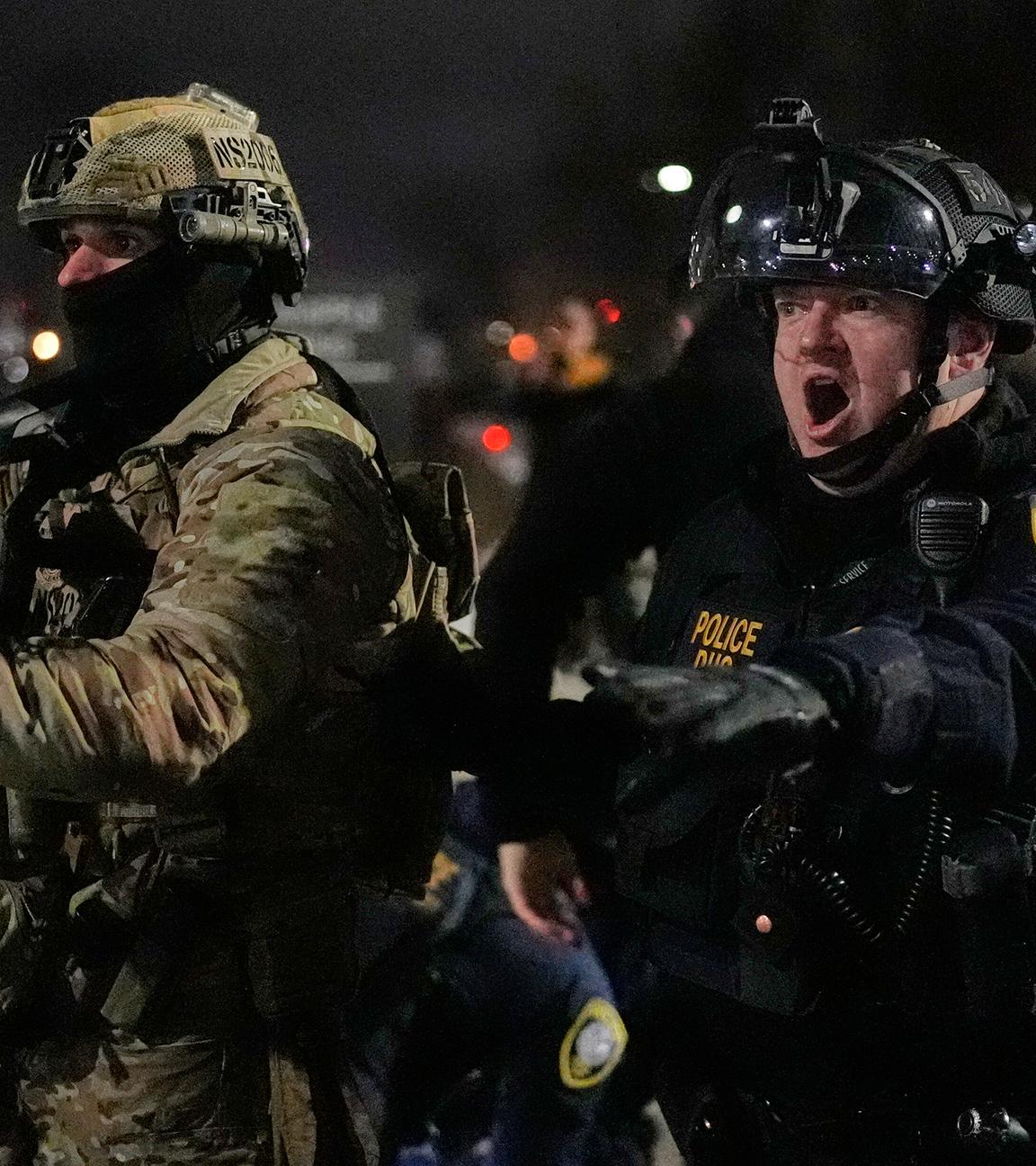 Bundesbeamte der Einwanderungsbehörde konfrontieren Demonstranten vor dem Bishop Henry Whipple Federal Building in Minneapolis.