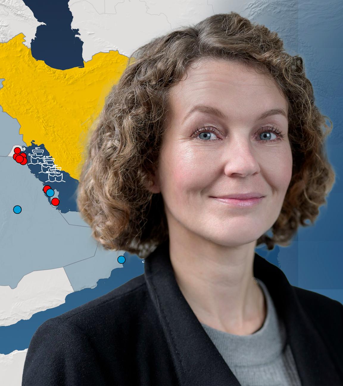 Die Nahost-Analystin Marie-Theres Sommerfeld vom GIDS im Vordergrund, im Hintergrund eine Karte des Iran mit seinen Atomprogrammen und eingezeichnete Flugzeugträger und Kampfschiffe der USA.