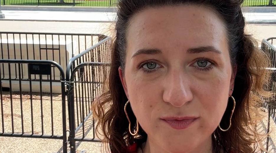 Eine Frau filmt sich draußen selbst, im Hintergrund das Weiße Haus und eine USA-Flagge