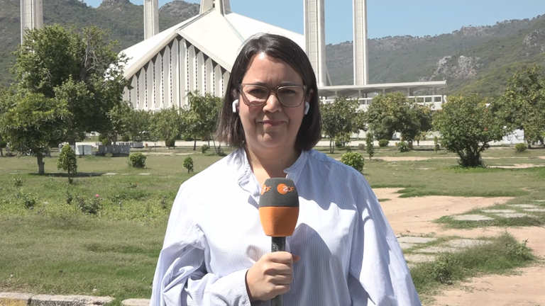 ZDF-Reporterin Phoebe Gaa vor einer Wiese mit Bäumen und einem weißen Gebäude in Islamabad