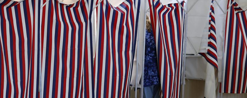 Von außerhalb der Wahlkabine sieht man eine Wählerin, die in der USA bei den Midterms in einer Wahlkabine steht.