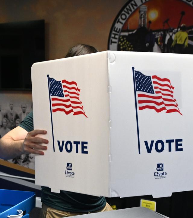 Ein Wahlhelfer richtet für die Midterms 2026 Wahlkabinen in einem Wahllokal ein.